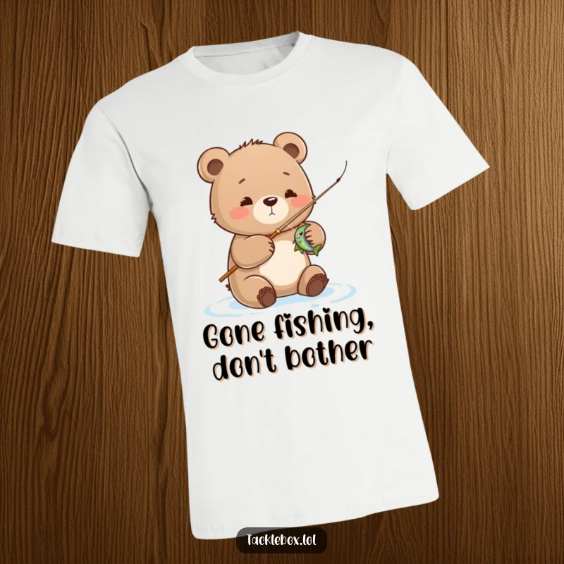 Funny bear cub t-shirt, joyfully reeling in a fish with a tiny rod, showcasing a cute fishing adventure and great humor.